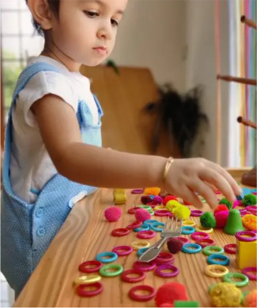 A kid wearing blue dress and playing with crafts at mother toddler program at sneha's imagination station